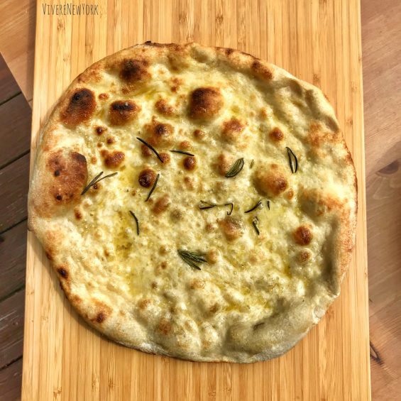 Freshly baked Neapolitan pizza with charred crust coming out of the Ooni Fyra portable pizza oven in a backyard in Upstate New York